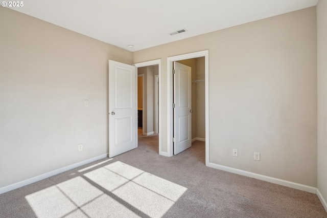 unfurnished bedroom featuring a spacious closet, light carpet, and a closet