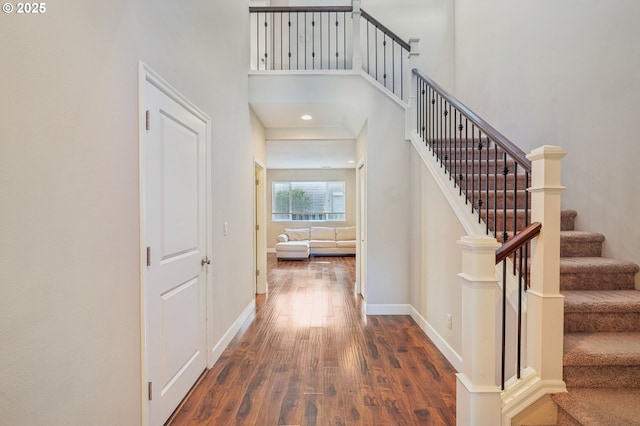 foyer entrance featuring dark wood-type flooring and a towering ceiling