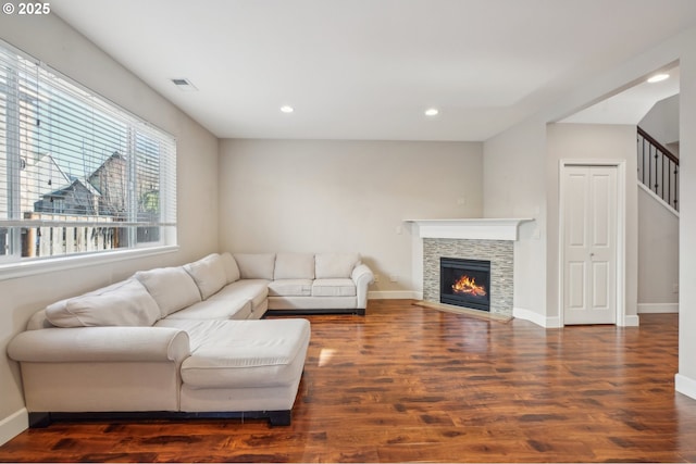 living room featuring dark hardwood / wood-style flooring and a stone fireplace