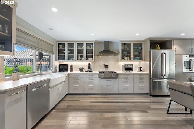 240 Greenridge Dr, Lake Oswego, OR 97035 - kitchen featuring appliances with stainless steel finishes, wall chimney range hood, light wood finished floors, tasteful backsplash, and recessed lighting