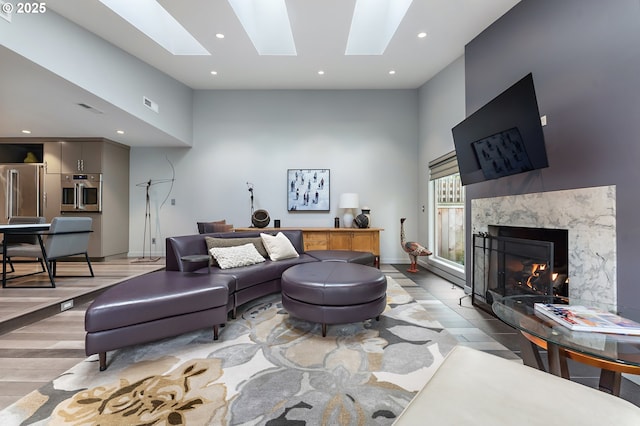 240 Greenridge Dr, Lake Oswego, OR 97035 - living room with a high ceiling, light wood-style floors, a skylight, a high end fireplace, and recessed lighting