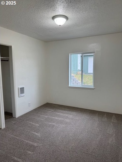 847 NE Jackson Ave, Myrtle Creek, OR 97457 - unfurnished bedroom with carpet, a textured ceiling, a closet, and heating unit
