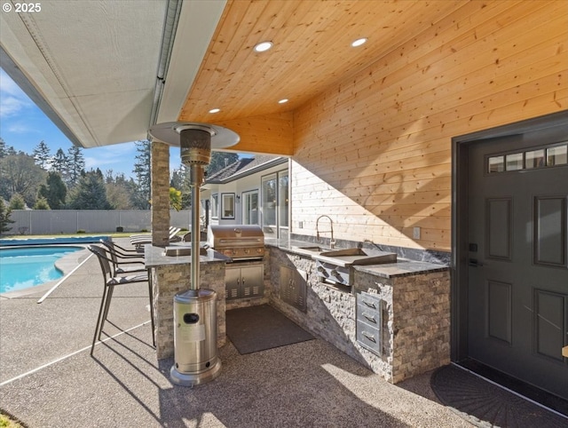 view of pool featuring an outdoor kitchen, a grill, a patio area, and an outdoor wet bar