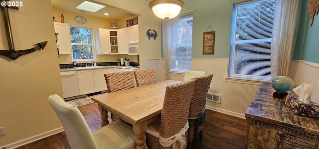 dining space with dark hardwood / wood-style flooring, a skylight, and sink