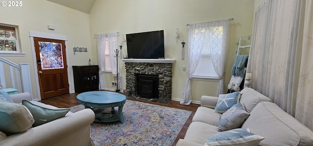 living room featuring a stone fireplace, dark wood-type flooring, and high vaulted ceiling