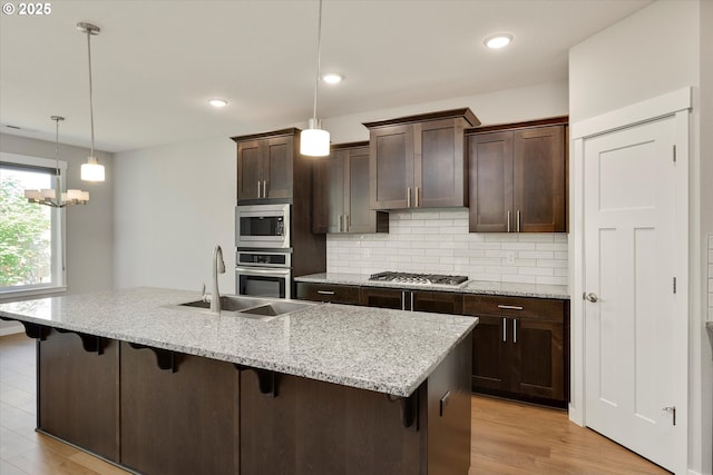 1059 S Walnut St, Canby, OR 97013 - kitchen with a sink, appliances with stainless steel finishes, decorative backsplash, a breakfast bar, and dark brown cabinetry