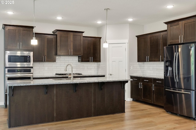 1059 S Walnut St, Canby, OR 97013 - kitchen with stainless steel appliances, a sink, a kitchen bar, dark brown cabinetry, and recessed lighting