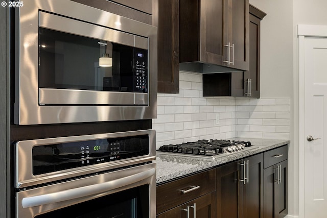 1059 S Walnut St, Canby, OR 97013 - kitchen featuring appliances with stainless steel finishes, dark brown cabinetry, tasteful backsplash, and light stone counters