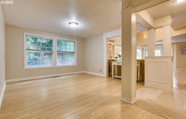 5706 SW Hamilton St, Portland, OR 97221 - unfurnished living room with a textured ceiling, ornate columns, plenty of natural light, and light wood-type flooring