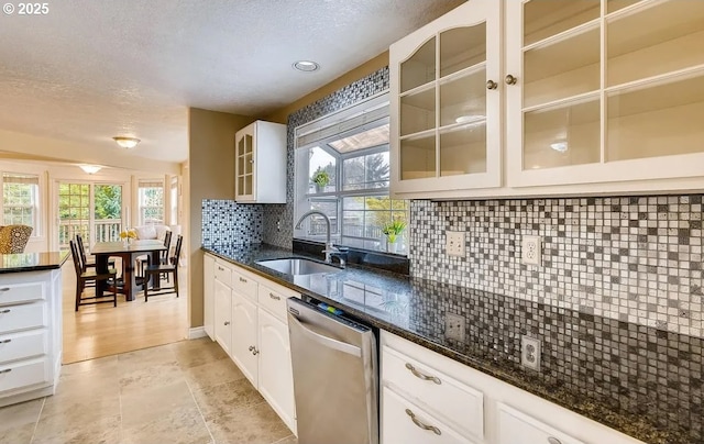 5706 SW Hamilton St, Portland, OR 97221 - kitchen with stainless steel dishwasher, a textured ceiling, tasteful backsplash, glass insert cabinets, and dark stone countertops