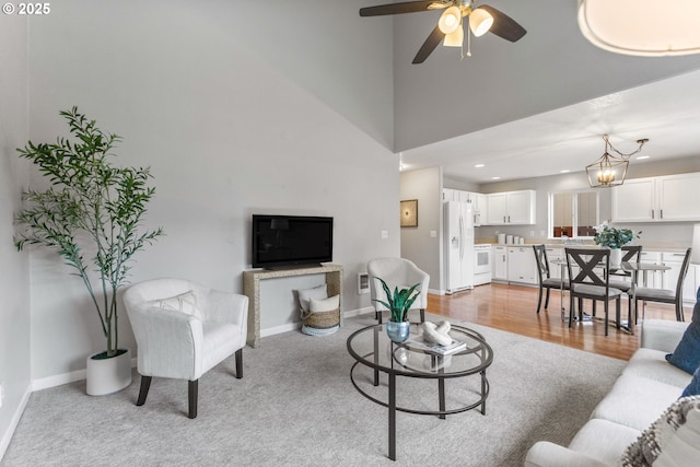 living room with baseboards, recessed lighting, a towering ceiling, ceiling fan with notable chandelier, and light wood-type flooring