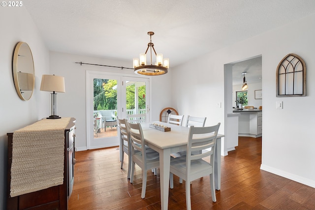 dining space featuring a healthy amount of sunlight, baseboards, dark wood-style floors, and a chandelier