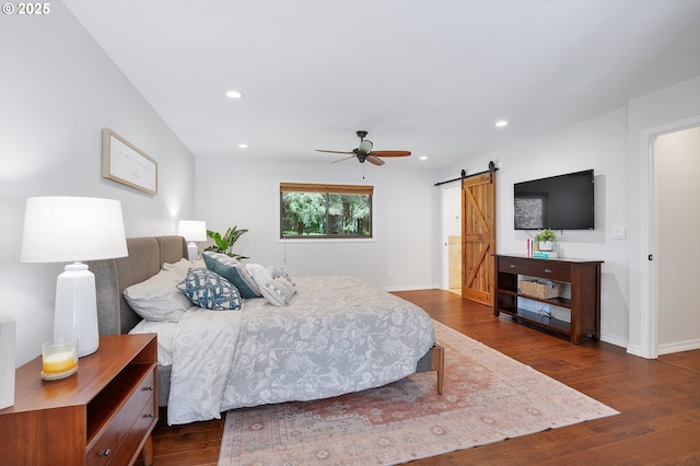 bedroom featuring dark wood-style flooring, recessed lighting, and a barn door