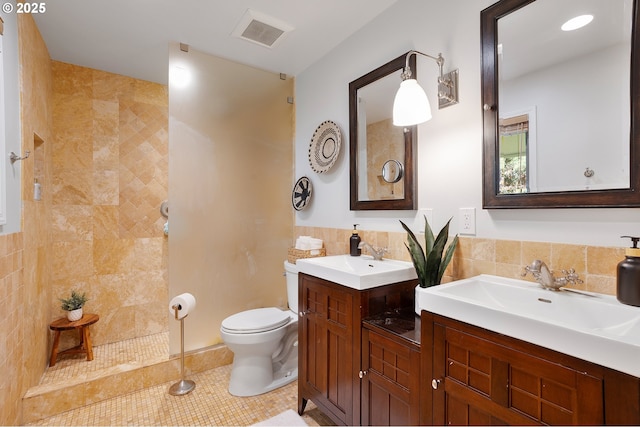 bathroom with a walk in shower, visible vents, a sink, and tile walls