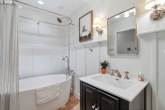 full bath with a freestanding bath, vanity, and stone finish floor