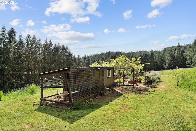 view of poultry coop featuring a yard and a wooded view