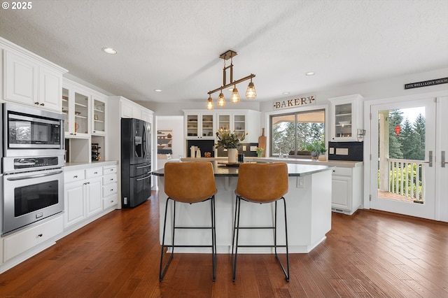 kitchen featuring a center island, appliances with stainless steel finishes, dark wood-style floors, and a kitchen breakfast bar