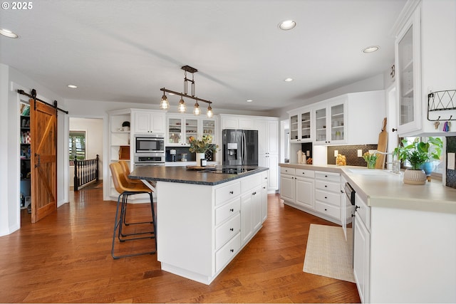 kitchen with backsplash, a kitchen island, appliances with stainless steel finishes, a barn door, and a sink
