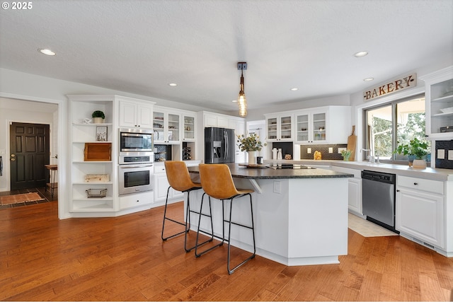 kitchen featuring open shelves, white cabinets, appliances with stainless steel finishes, and a kitchen island