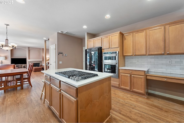 3140 Sabo Ln, West Linn, OR 97068 - kitchen with appliances with stainless steel finishes, open floor plan, light wood-style floors, backsplash, and a center island