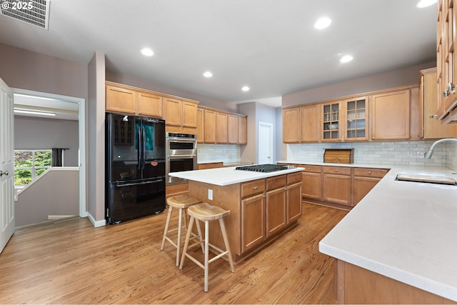 3140 Sabo Ln, West Linn, OR 97068 - kitchen with appliances with stainless steel finishes, a sink, a center island, light wood-style floors, and a kitchen bar