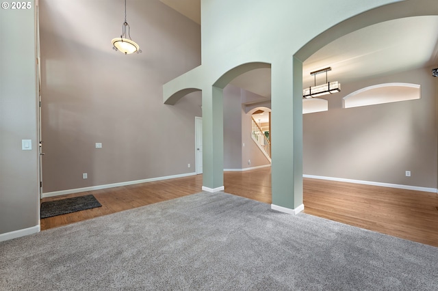 3140 Sabo Ln, West Linn, OR 97068 - unfurnished room with carpet flooring, a towering ceiling, arched walkways, baseboards, and wood finished floors
