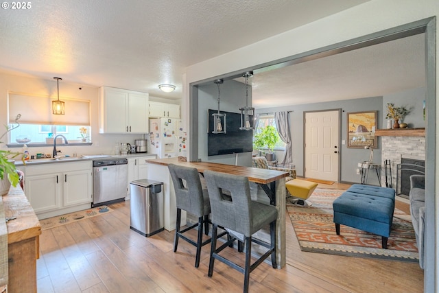 kitchen featuring a sink, white cabinets, white refrigerator with ice dispenser, light wood-style floors, and dishwasher