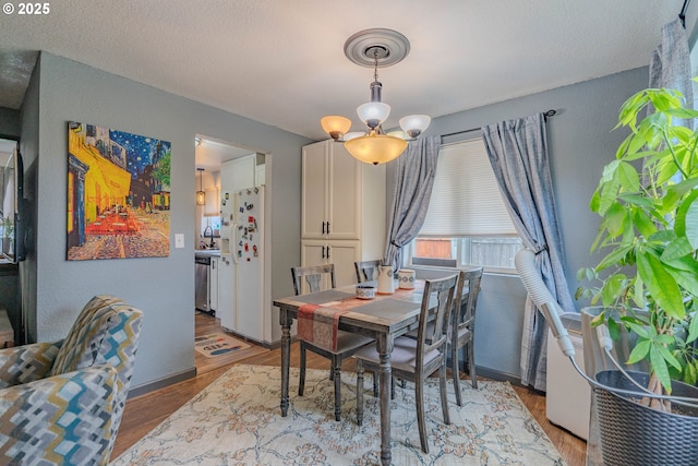 dining space featuring an inviting chandelier, wood finished floors, and baseboards