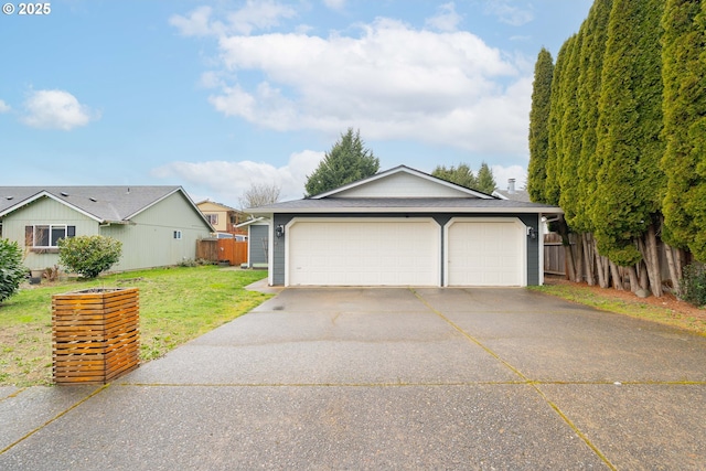 view of front of home with a front yard, concrete driveway, fence, and a garage