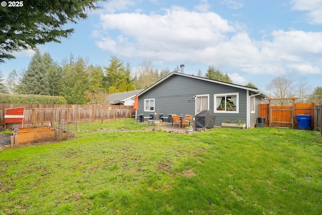 back of house featuring a fenced backyard, a patio area, a yard, and a gate