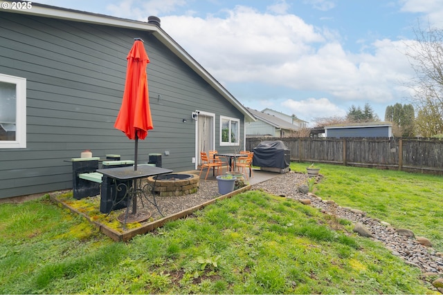 rear view of house featuring a patio area, a lawn, a fire pit, and a fenced backyard