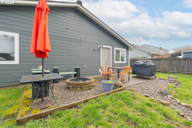 rear view of house featuring a patio, fence, and an outdoor fire pit