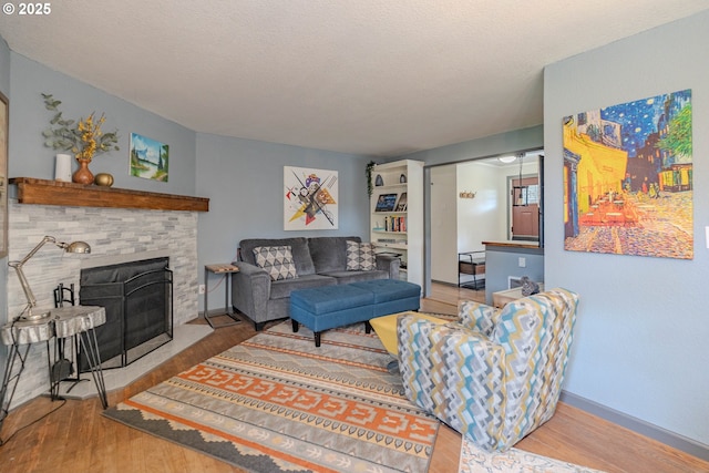 living room featuring a fireplace with flush hearth, a textured ceiling, and wood finished floors