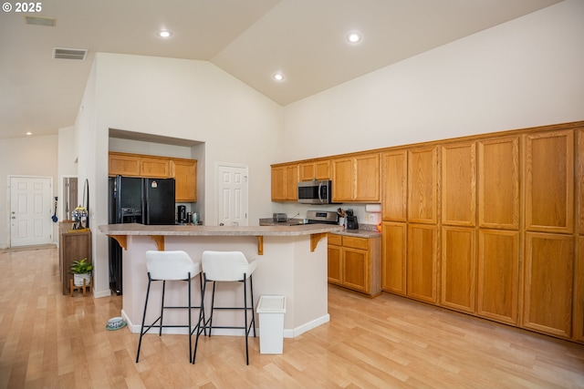 5419 Baden Way, Eugene, OR 97402 - kitchen with stainless steel microwave, black fridge with ice dispenser, high vaulted ceiling, electric stove, and a breakfast bar