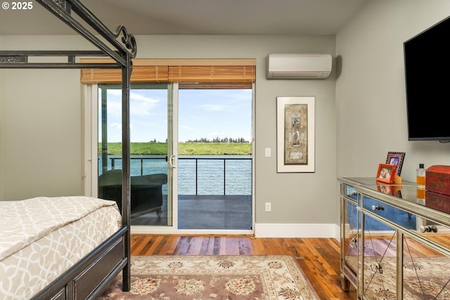 23586 NW St Helens Rd Unit U12, Portland, OR 97231 - bedroom featuring a wall unit AC, access to exterior, wood finished floors, and baseboards