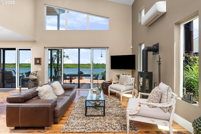 23586 NW St Helens Rd Unit U12, Portland, OR 97231 - living room with a wood stove, a wall unit AC, light wood-style flooring, a high ceiling, and healthy amount of natural light