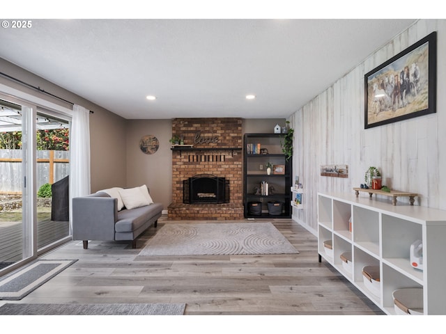 living area featuring recessed lighting, wood walls, wood finished floors, and a fireplace
