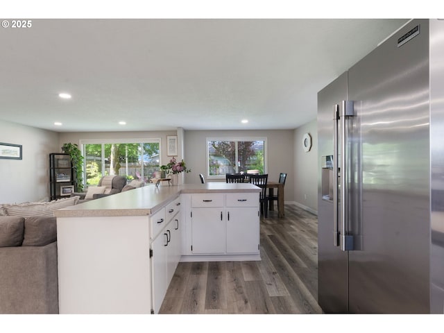 kitchen featuring high end fridge, light wood-style floors, light countertops, recessed lighting, and open floor plan