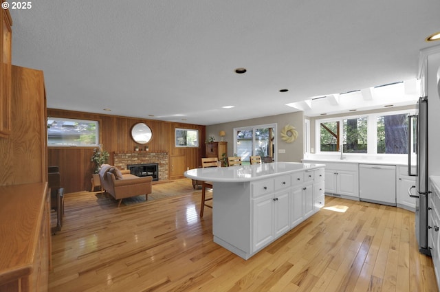 kitchen featuring white dishwasher, plenty of natural light, light wood-type flooring, and open floor plan