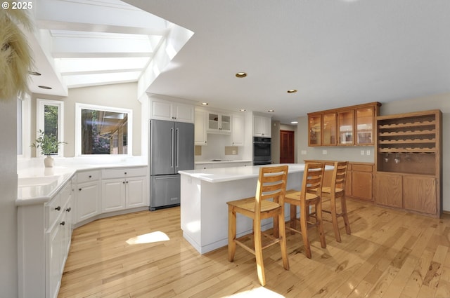 kitchen featuring glass insert cabinets, a center island, light wood-style flooring, and high end fridge
