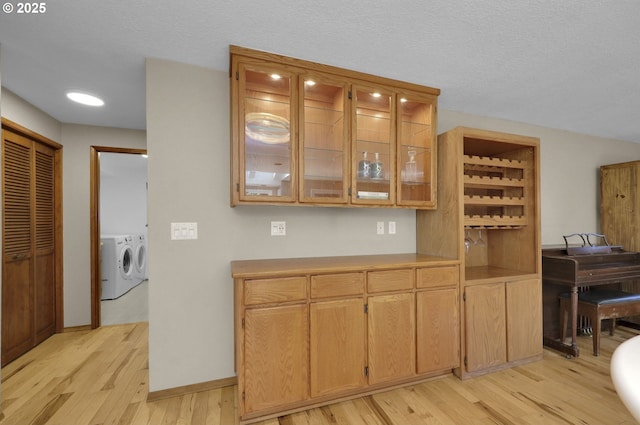 bar with light wood-style floors, separate washer and dryer, and baseboards