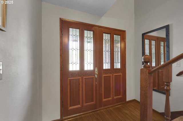entryway featuring baseboards, dark wood-style flooring, and stairs