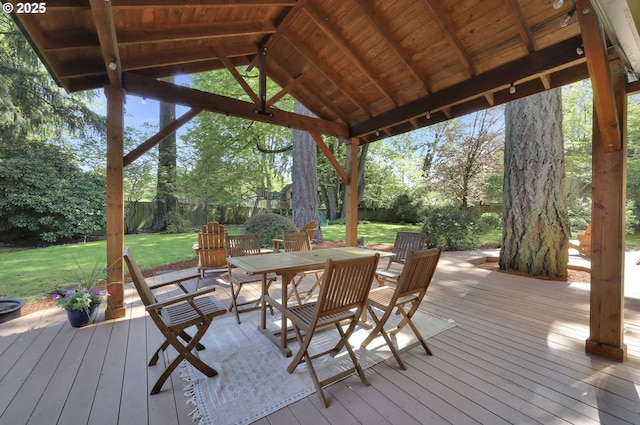 wooden deck featuring a lawn, outdoor dining space, and a fenced backyard