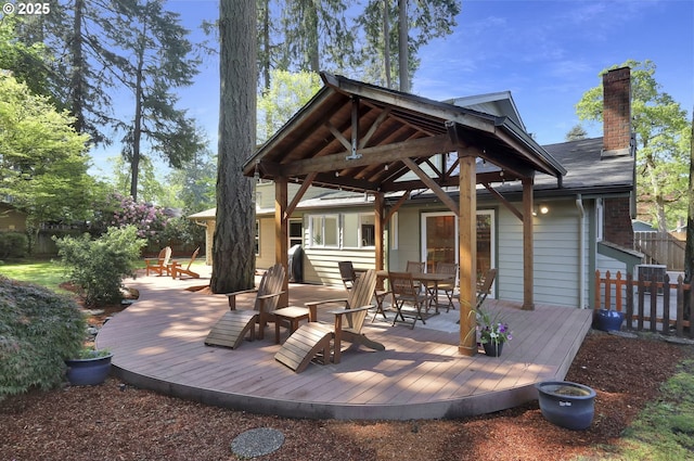 wooden deck with outdoor dining area, fence, and a gazebo