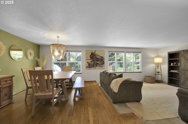 living area with a textured ceiling, wood finished floors, and a notable chandelier