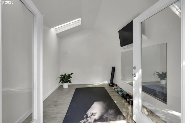 exercise area featuring lofted ceiling with skylight and wood finished floors