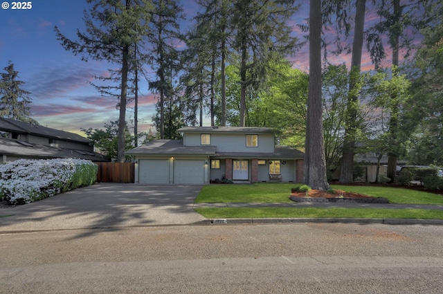traditional home featuring an attached garage, aphalt driveway, fence, brick siding, and a lawn