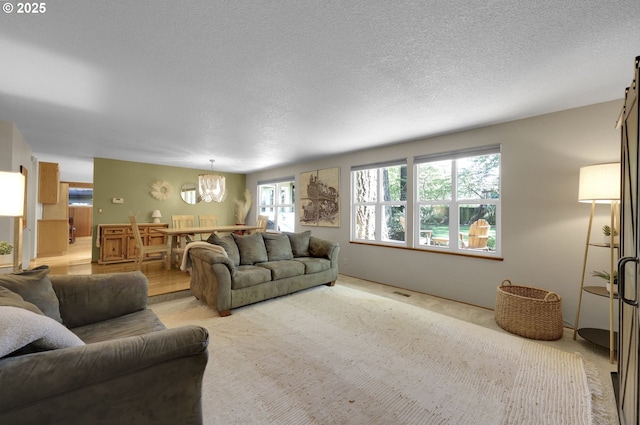 living area featuring visible vents, a textured ceiling, a notable chandelier, and light carpet