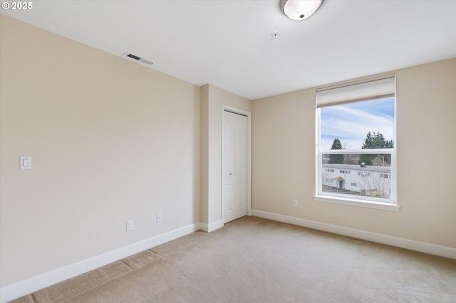 unfurnished bedroom featuring light carpet and a closet