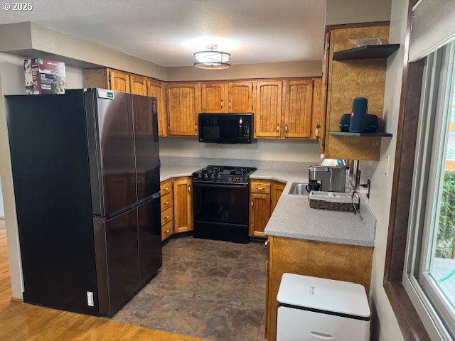 18622 SE Stephens Cir, Portland, OR 97233 - kitchen featuring black appliances, open shelves, light countertops, and brown cabinetry